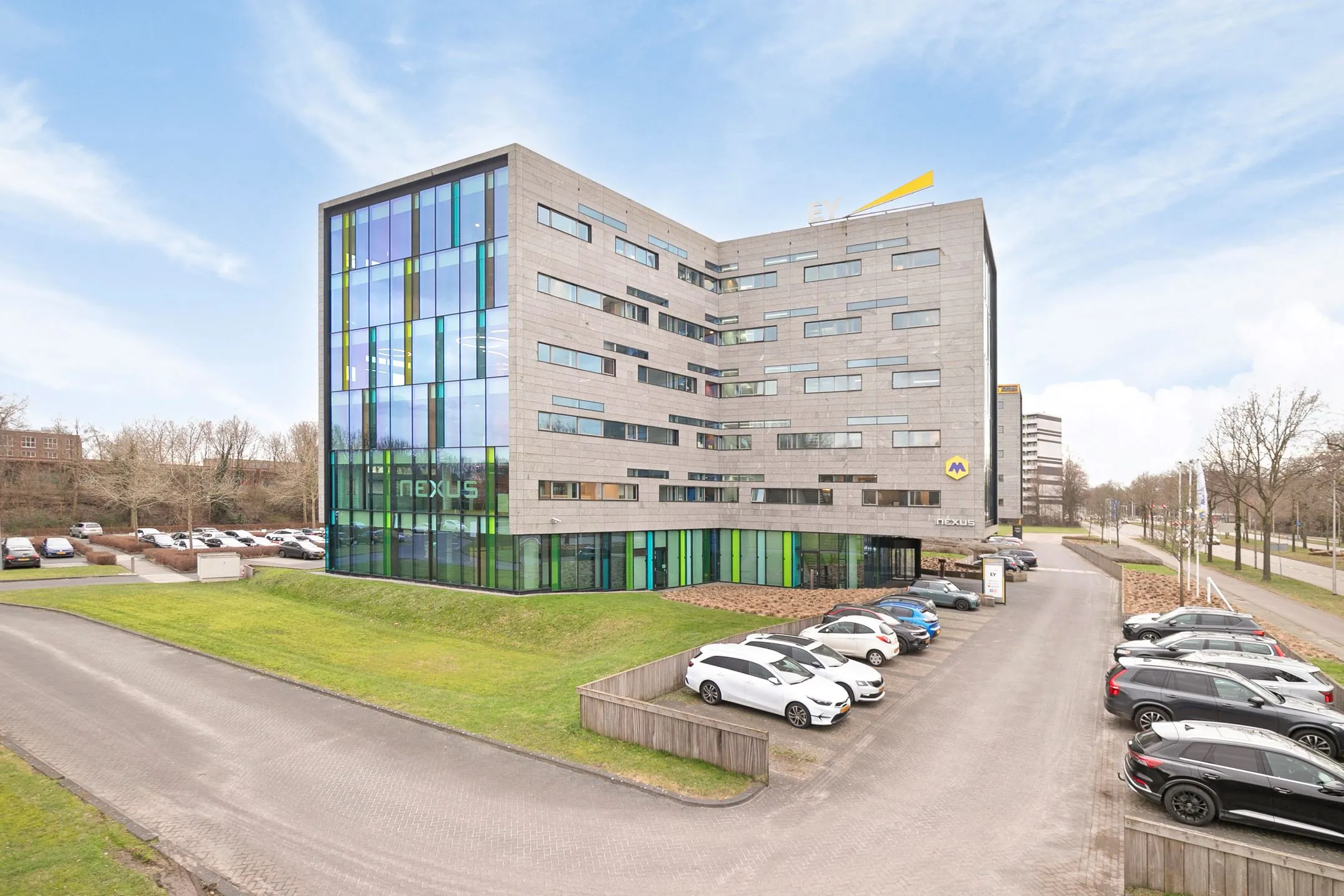 Modern kantoorgebouw met de naam Nexus aan de Zwartewaterallee 56, met parkeergelegenheid ervoor.