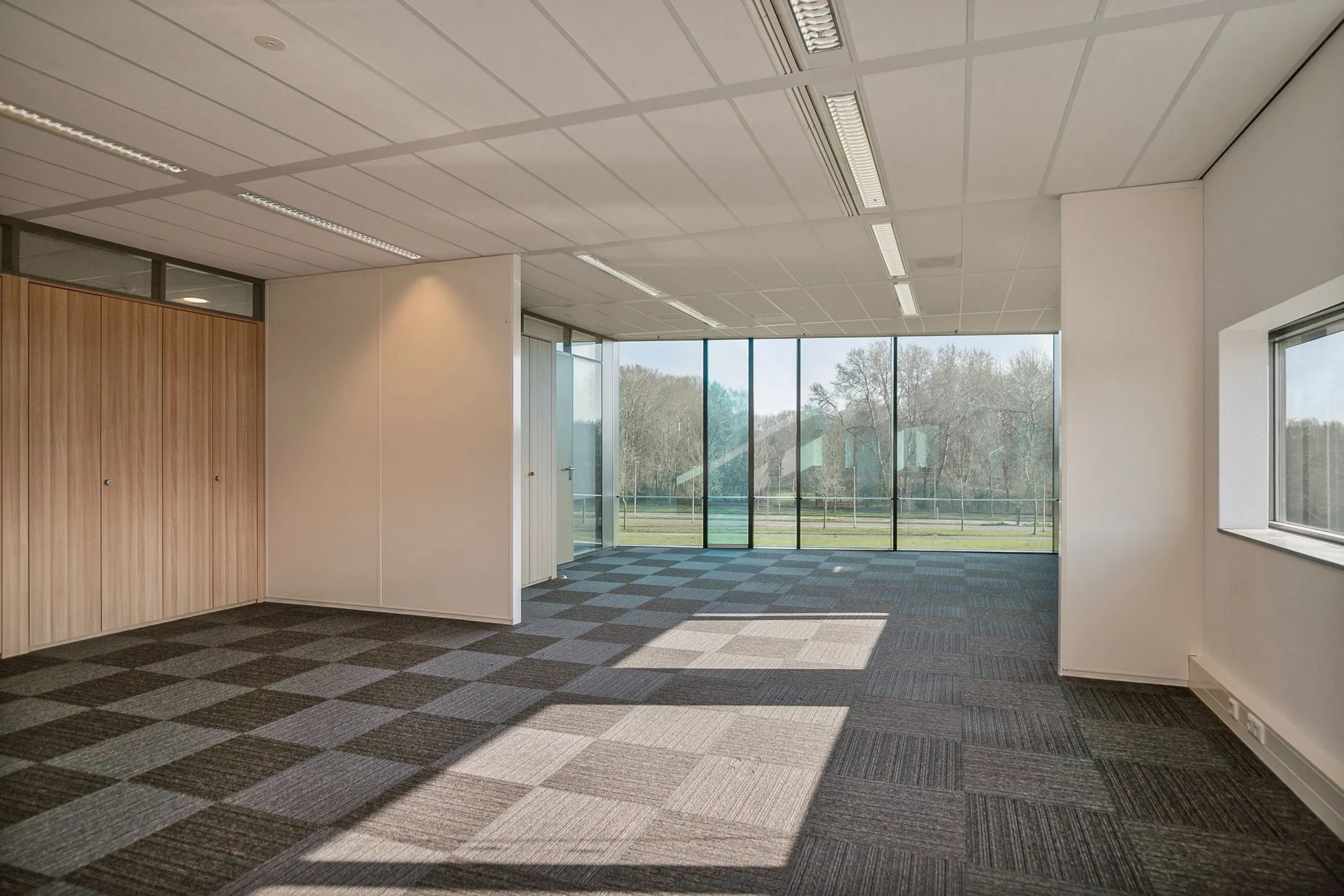 Licht en modern kantoorinterieur aan de Zwartewaterallee 56 met grote ramen en uitzicht op bomen.