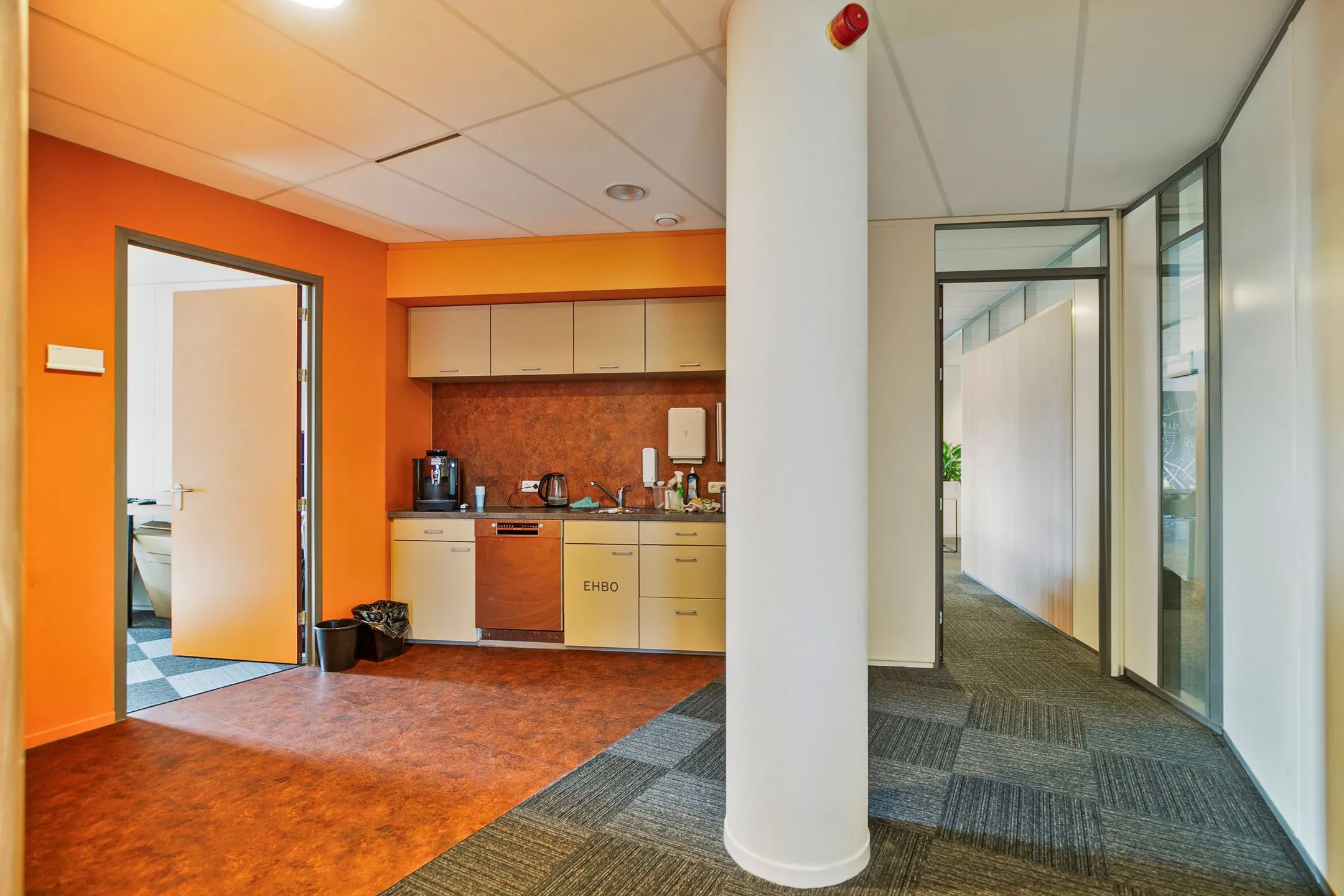 Kleine kantoorkeuken met koffiezetapparaat, gootsteen en EHBO-kast aan de Zwartewaterallee 56.