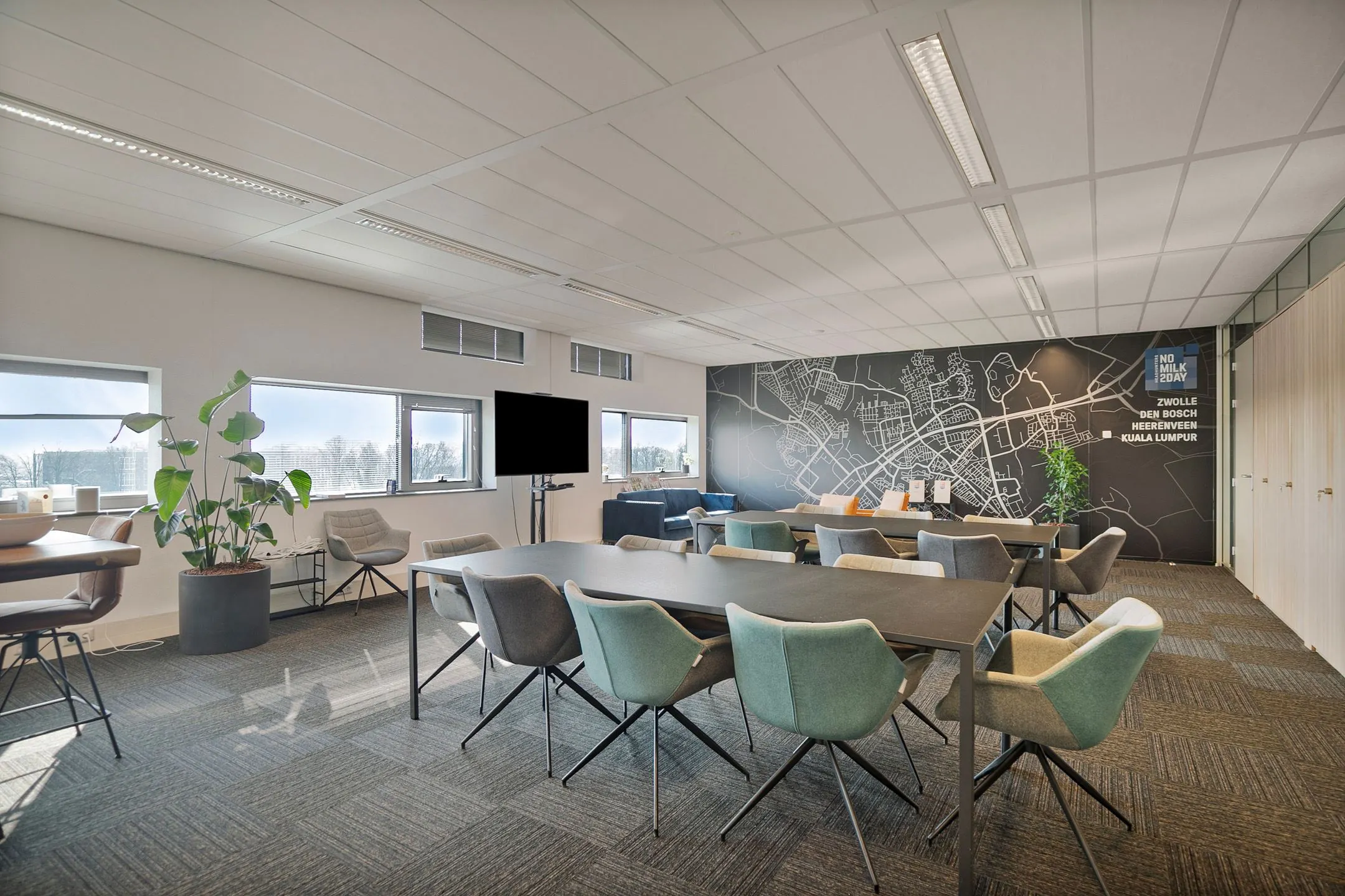 Moderne vergaderruimte met grote ramen, kleurrijke stoelen en een wand met stadsplattegrond bij Zwartewaterallee 56.