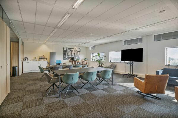 Moderne vergaderruimte aan de Zwartewaterallee 56 met vergadertafels, stoelen, koffiecorner en groot presentatiescherm.