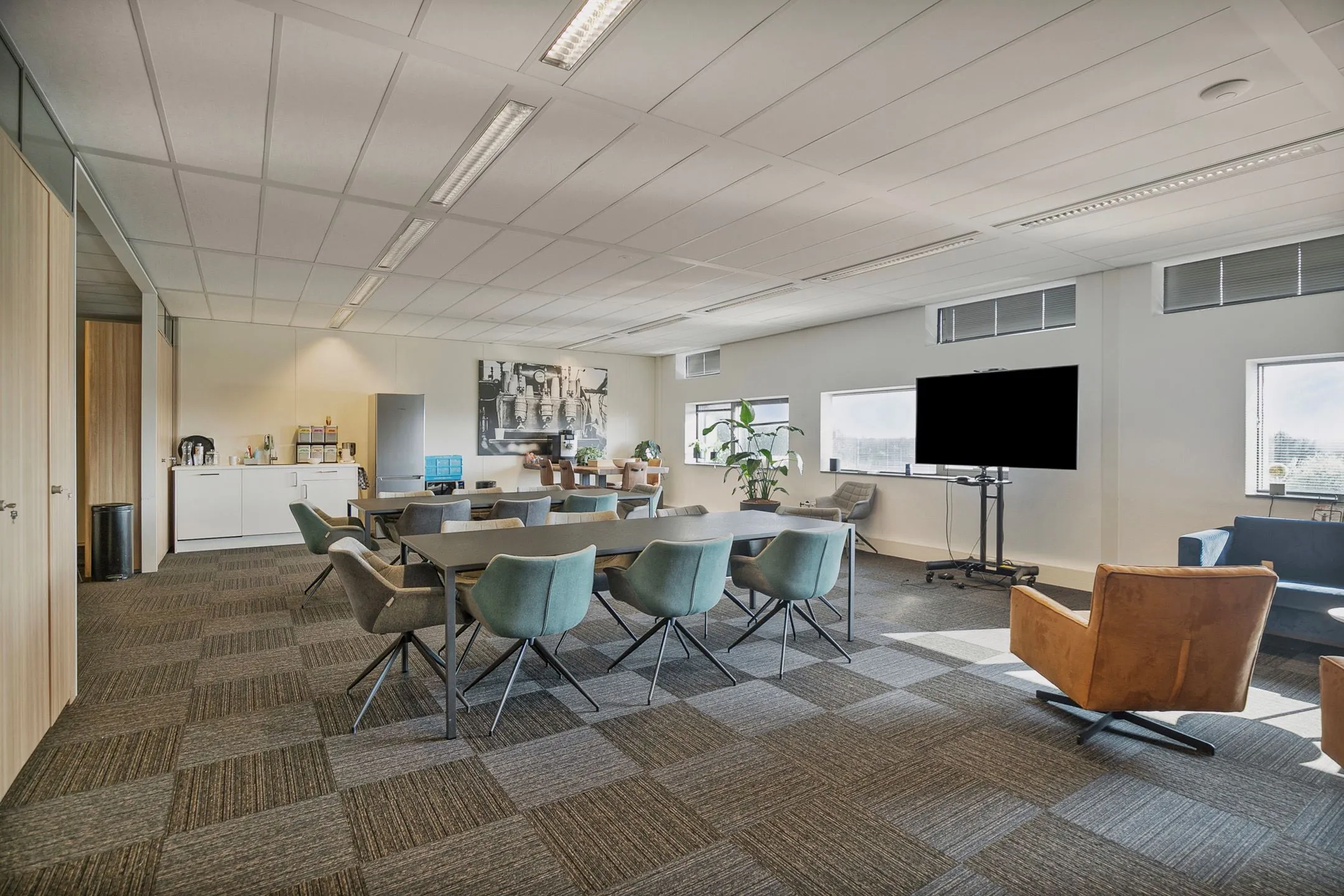 Moderne vergaderruimte aan de Zwartewaterallee 56 met vergadertafels, stoelen, koffiecorner en groot presentatiescherm.