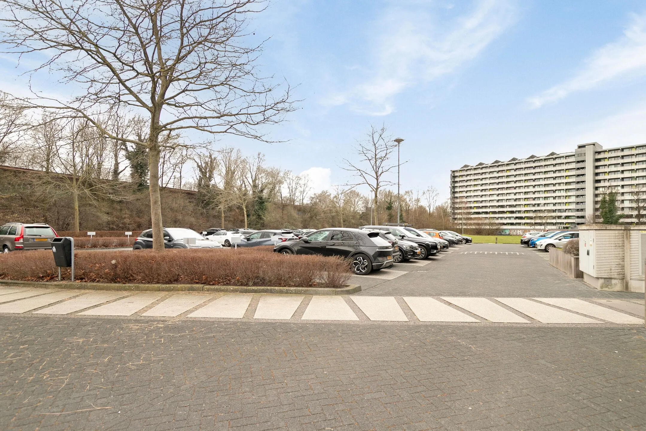 Parkeerterrein bij Zwartewaterallee 56 met geparkeerde auto's en een groot appartementencomplex op de achtergrond.