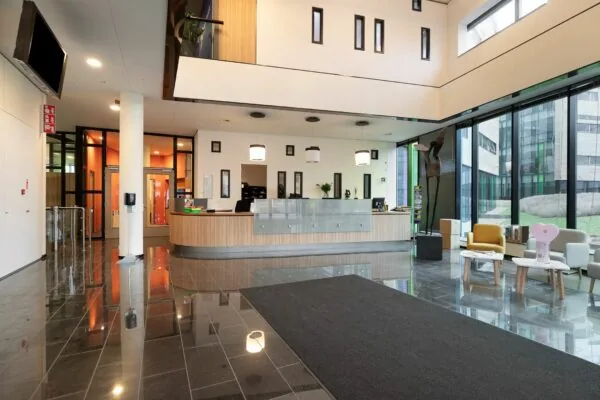 Moderne ontvangsthal met balie, zitgedeelte en grote ramen in het gebouw aan de Zwartewaterallee 56.