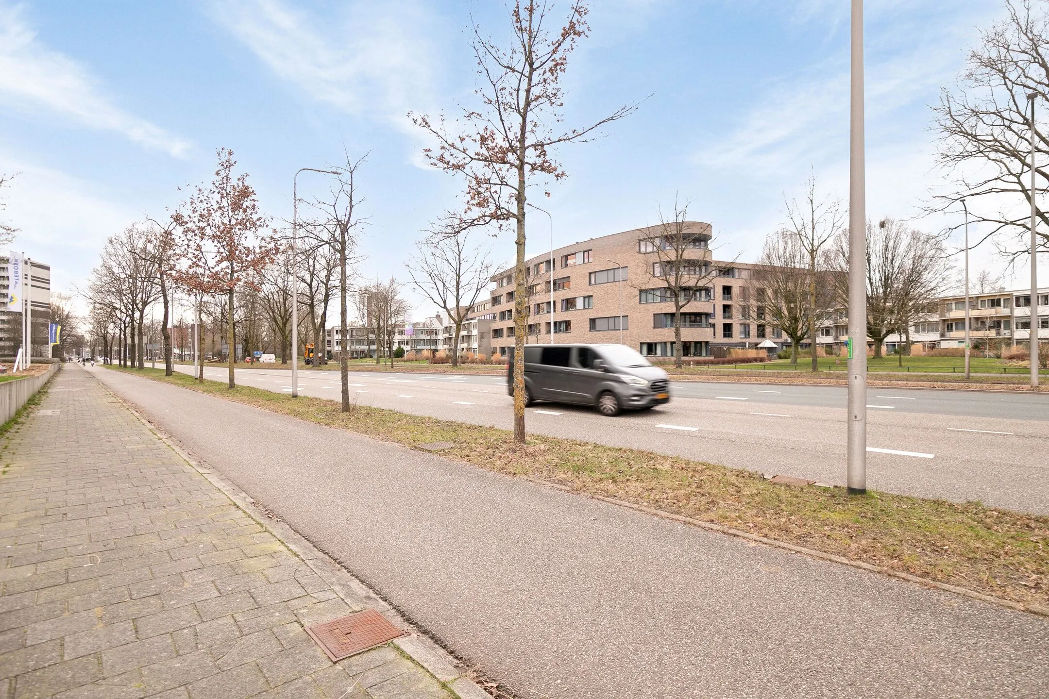 Moderne appartementsgebouwen aan de Zwartewaterallee met een rijdende bestelbus op de voorgrond.