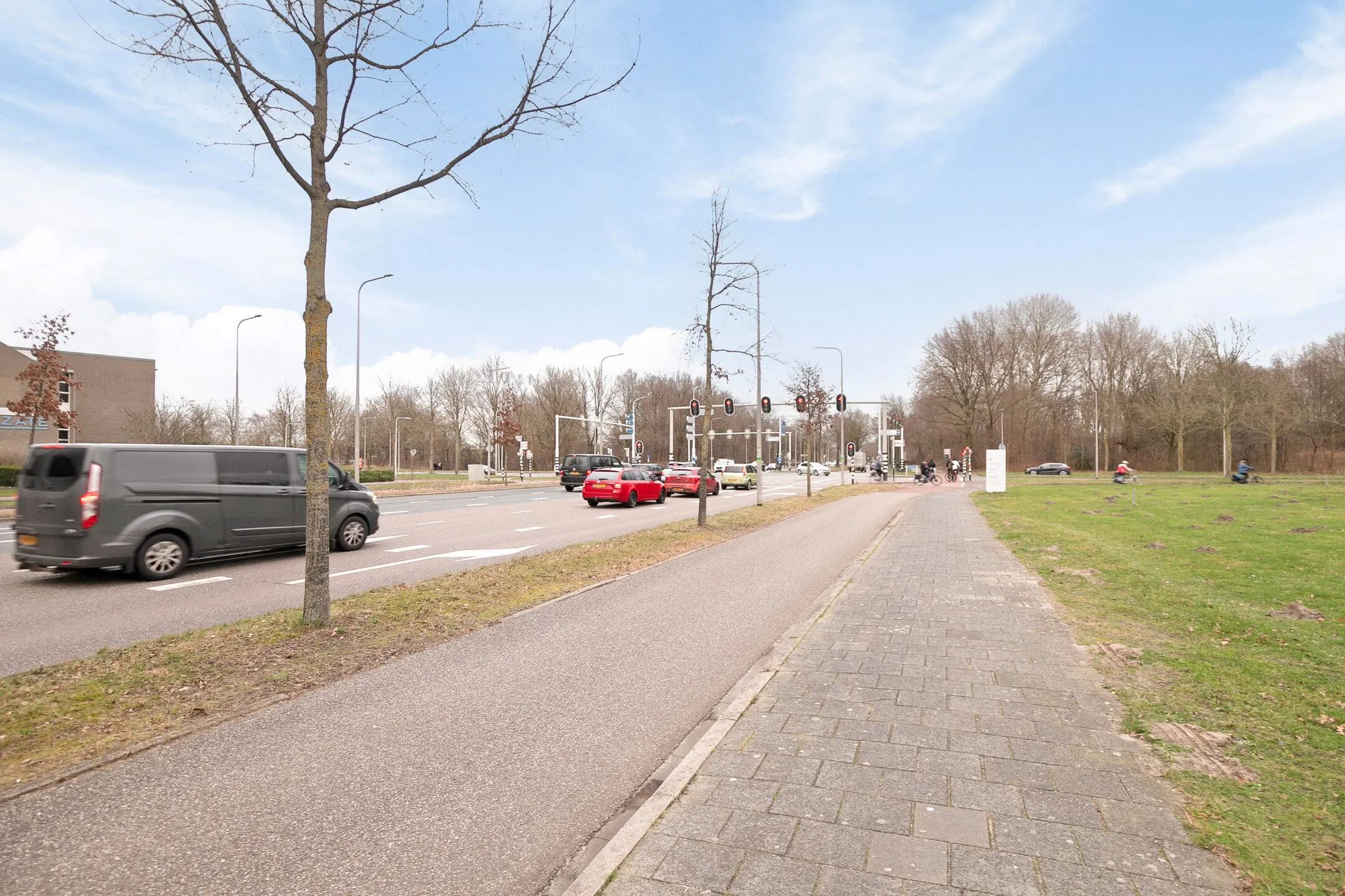 Drukke kruising met stoplichten op de Zwartewaterallee, gezien vanaf het fietspad en trottoir.