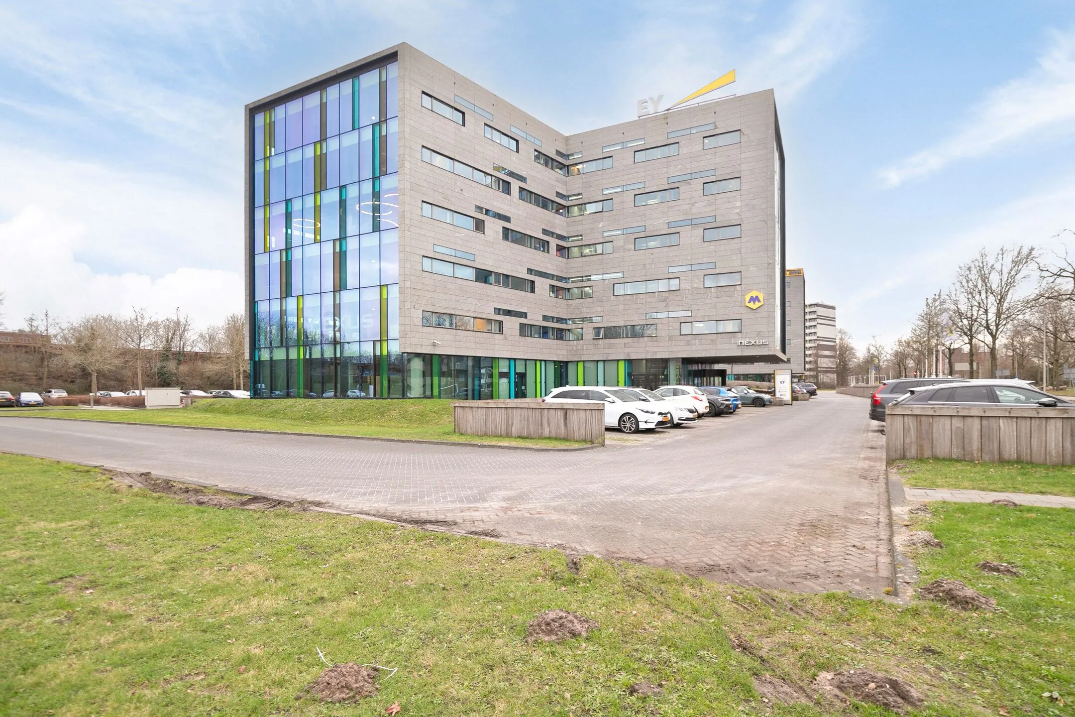 Modern kantoorgebouw aan de Zwartewaterallee 56 met parkeerplaatsen en kleurrijke glazen gevel.