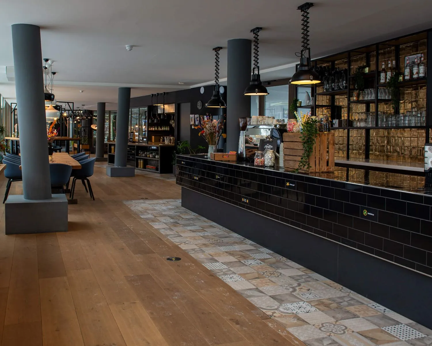 Moderne koffietobar in Zwolle met houten vloer, zwarte tegelbalie en industriële inrichting.