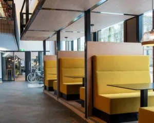 Moderne zithoeken met gele banken en zwarte tafels in een licht en open interieur in Zwolle.