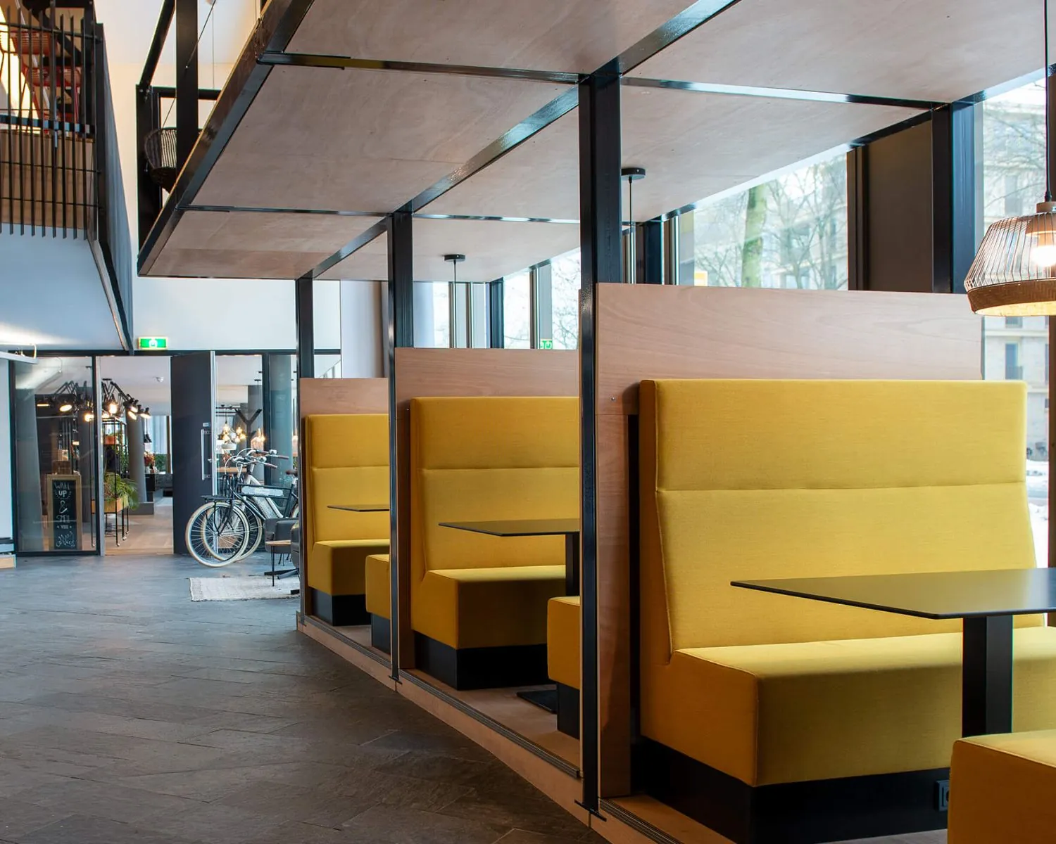Moderne zithoeken met gele banken en zwarte tafels in een licht en open interieur in Zwolle.