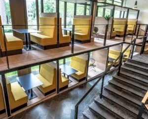 Moderne werk- of overlegruimte in Zwolle met tweelaagse gele zitnissen en grote ramen.