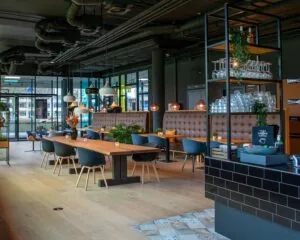 Modern ingerichte horecaruimte in Zwolle nabij de A28 met houten tafels, gestoffeerde zitbanken en een open zithoek.