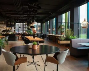 Modern ingericht restaurant aan de A28 bij Zwolle met houten vloeren, zwarte tafels en veel planten.