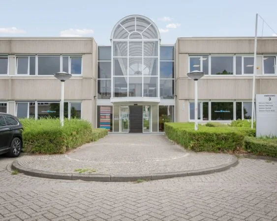Vooraanzicht van een modern kantoorgebouw aan de Energieweg 3, met glazen entree en bord met bedrijfsnamen van Veltman Uitgevers.