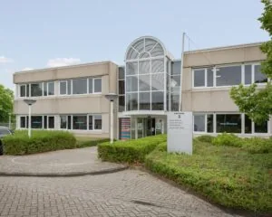 Vooraanzicht van een modern kantoorgebouw aan de Energieweg 3 met bedrijven van Uitgeverij Veltman.