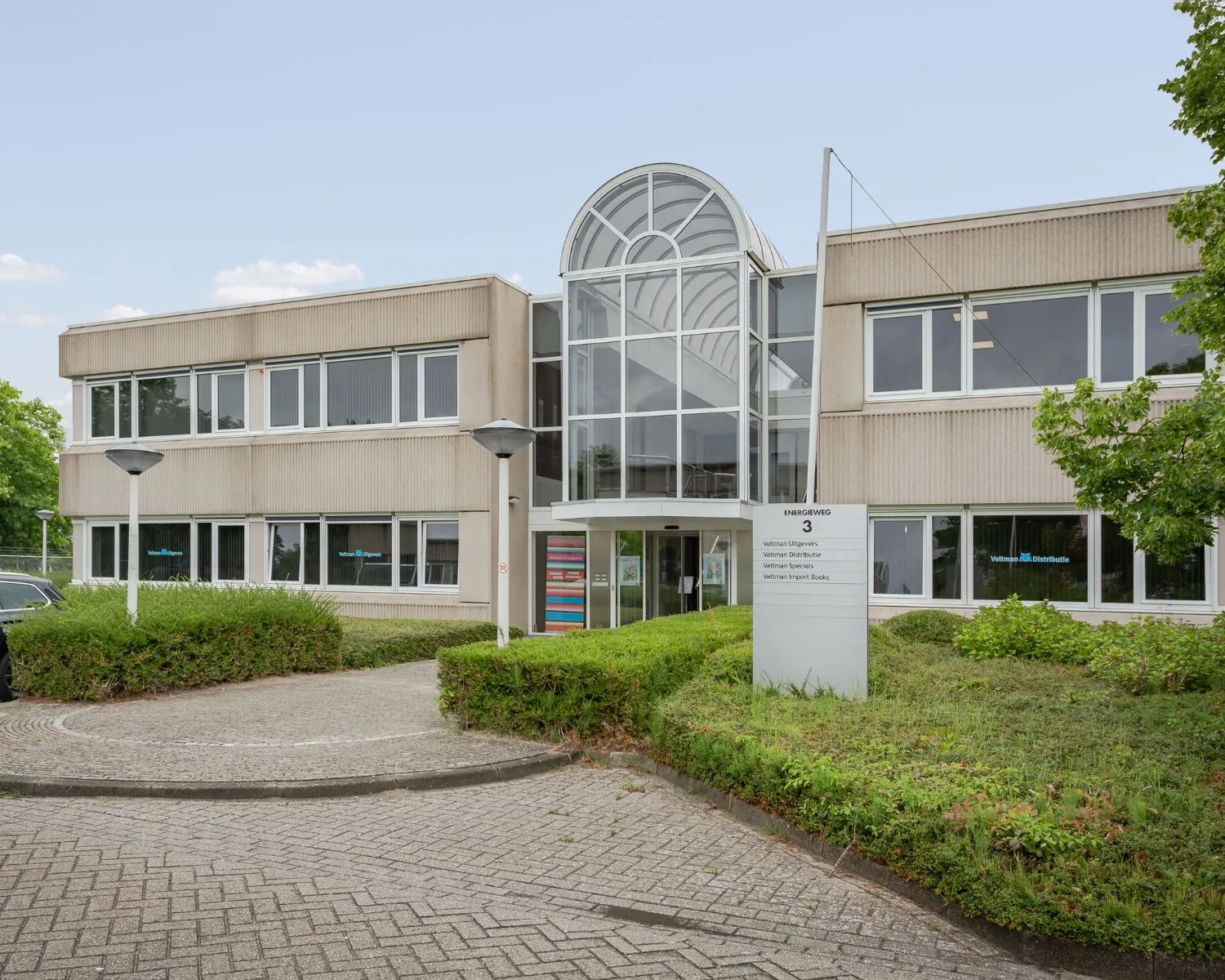 Vooraanzicht van een modern kantoorgebouw aan de Energieweg 3 met bedrijven van Uitgeverij Veltman.