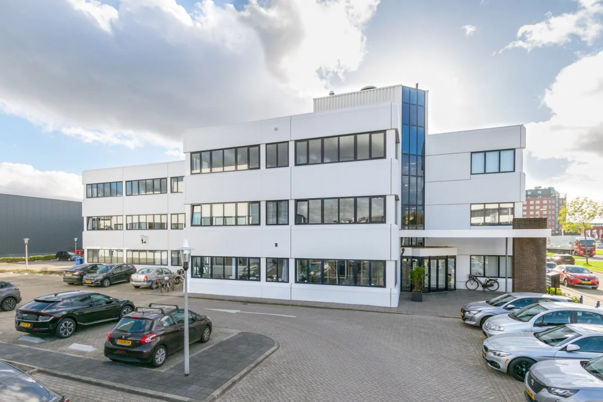 Modern wit kantoorgebouw aan de Atoomweg 350 met parkeerplaatsen en fietsenrek voor de ingang.