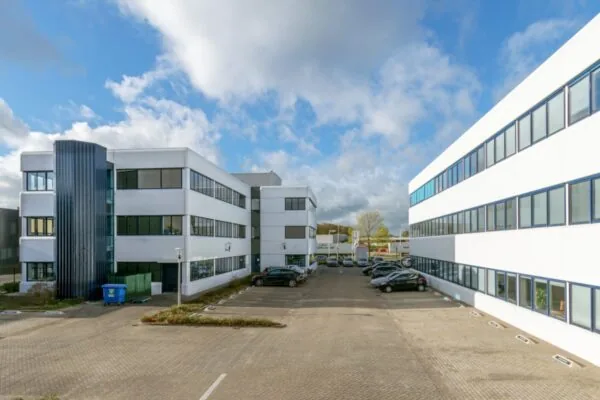 Twee witte kantoorgebouwen aan de Atoomweg 350 met een parkeerterrein ertussen onder een deels bewolkte lucht.