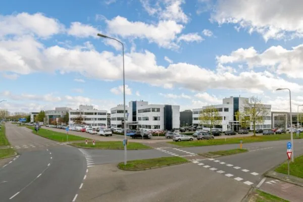 Zakelijk kantoorgebouw aan de Atoomweg 350 met parkeerplaatsen en omliggende wegen onder een deels bewolkte lucht.