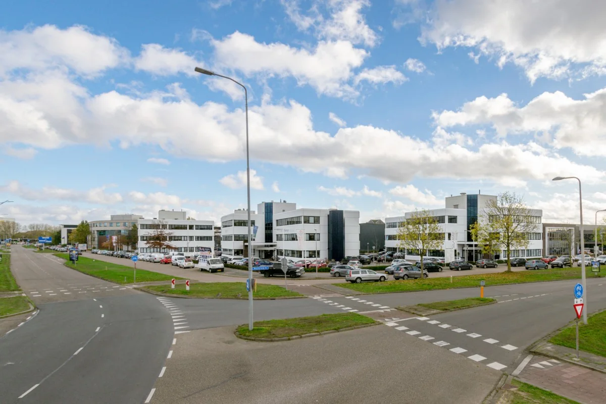 Zakelijk kantoorgebouw aan de Atoomweg 350 met parkeerplaatsen en omliggende wegen onder een deels bewolkte lucht.