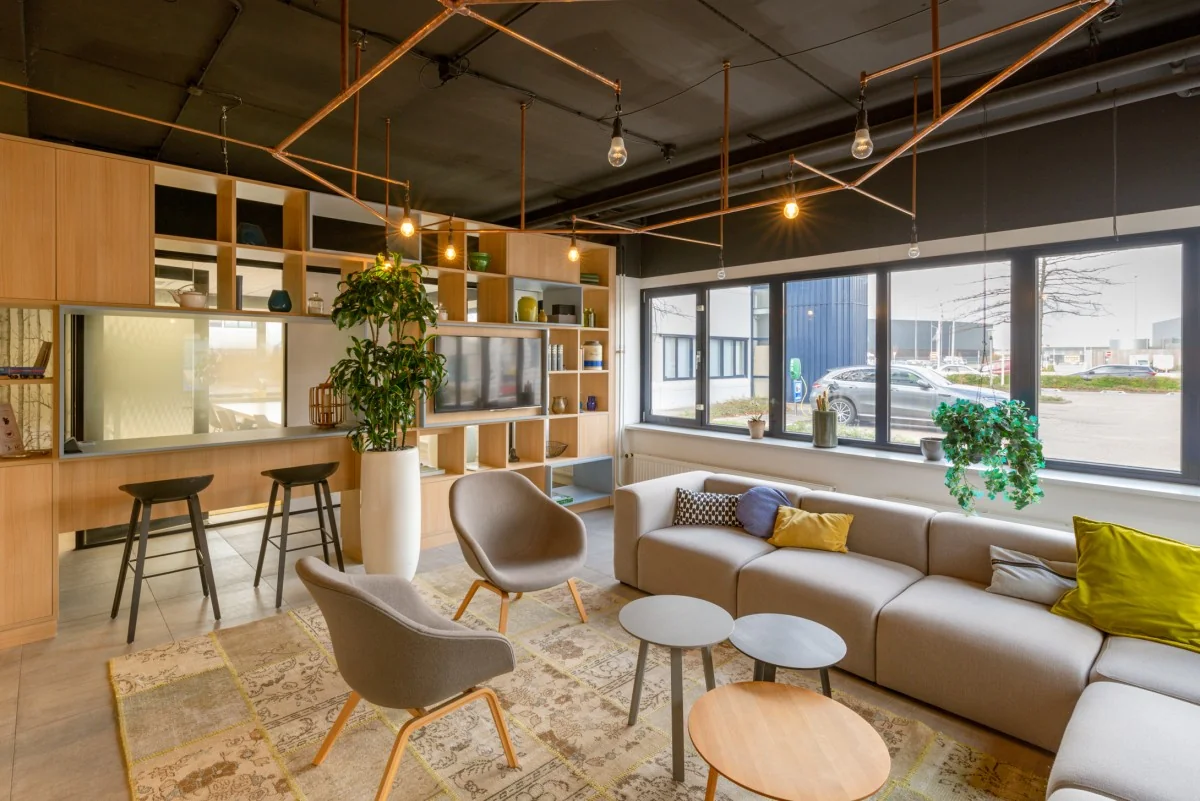 Moderne en gezellige loungehoek in kantoor Atoomweg 400 met comfortabele zitplaatsen, planten en grote ramen.