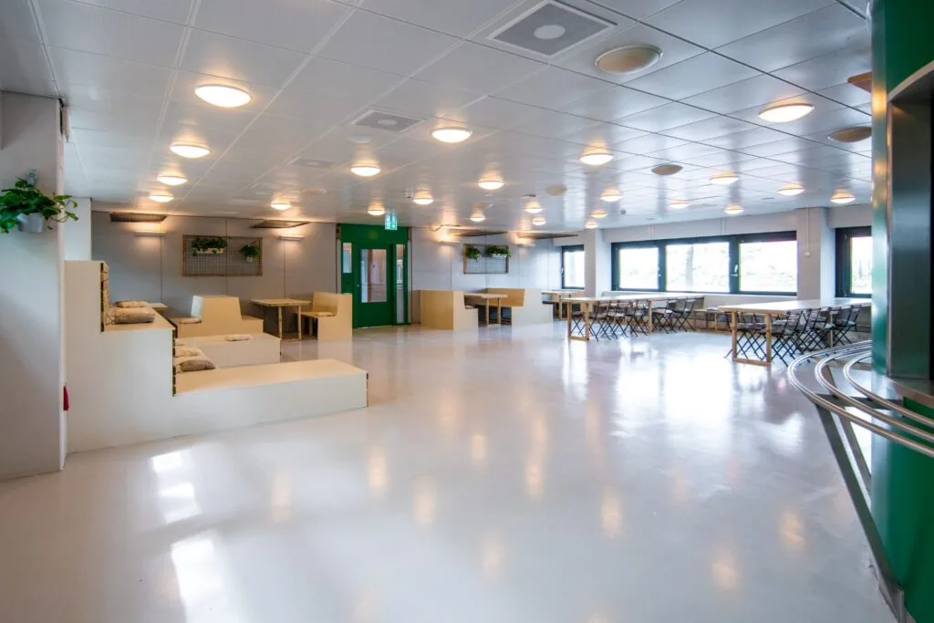 Ruime en moderne gemeenschappelijke zitruimte aan de Bernadottelaan met tafels, banken en veel natuurlijk licht.