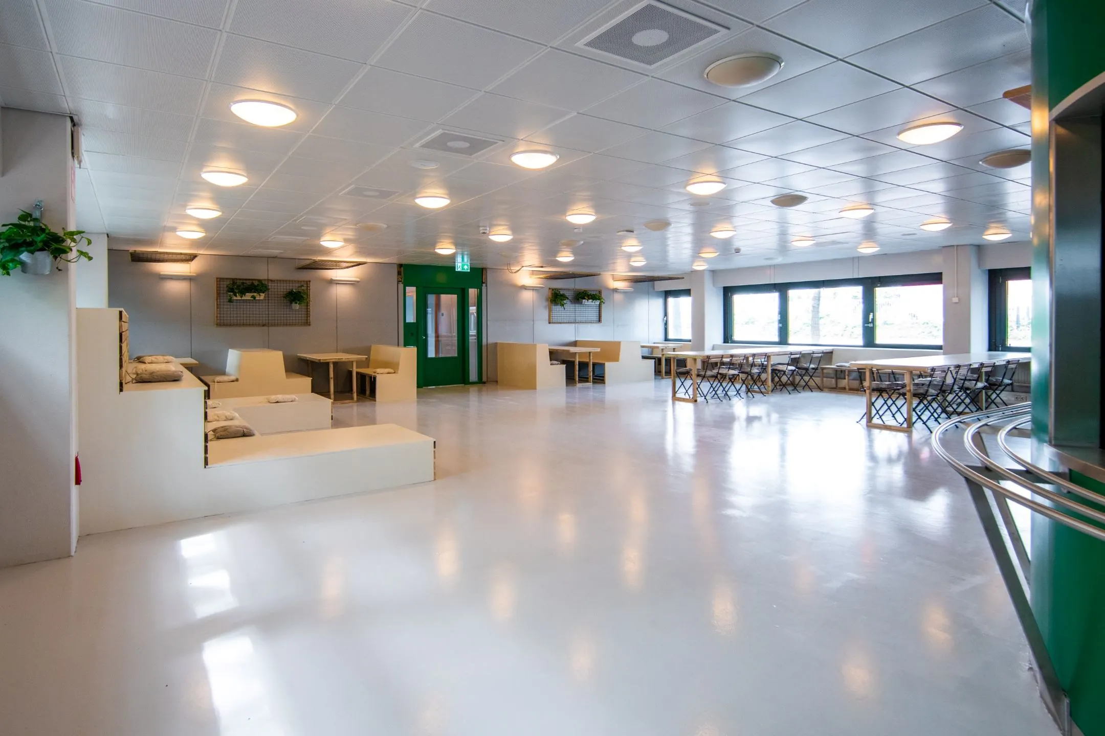 Ruime en moderne gemeenschappelijke zitruimte aan de Bernadottelaan met tafels, banken en veel natuurlijk licht.