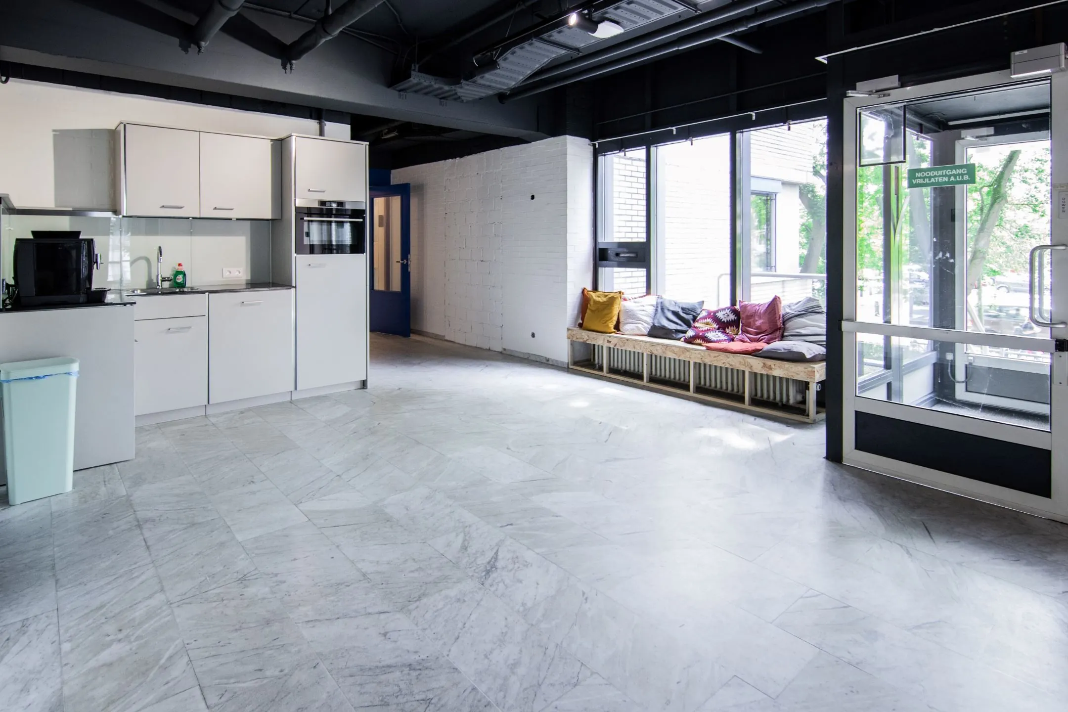 Moderne, lichte gemeenschappelijke ruimte aan de Bernadottelaan met een keuken, zitbank en glazen nooddeur.