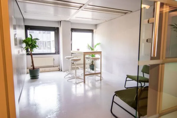 Lichte en moderne vergaderruimte aan de Bernadottelaan met hoge tafel, barkrukken en groene kamerplanten.