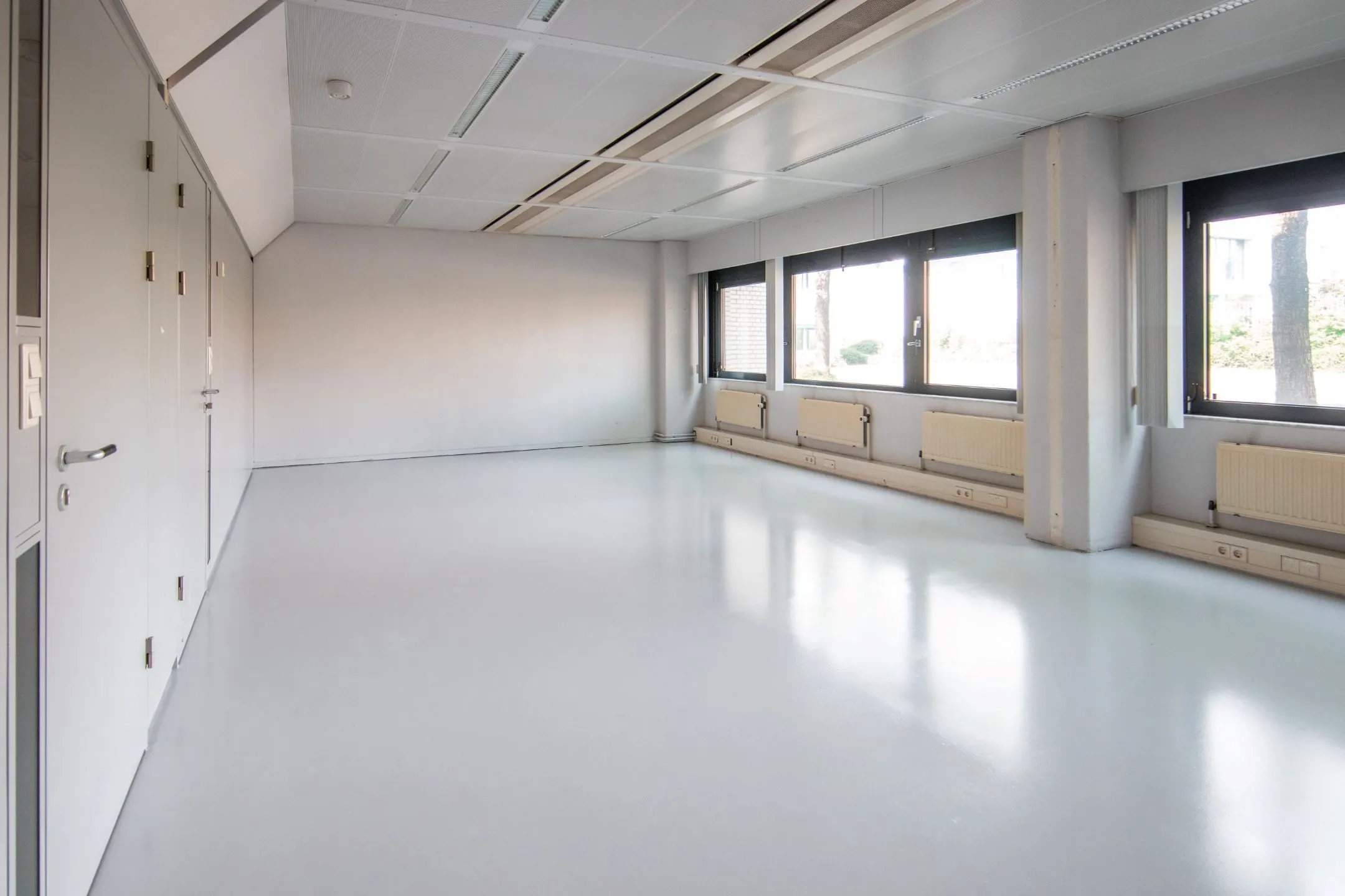 Lichte, lege kantoorruimte aan de Bernadottelaan met grote ramen en witte vloer.