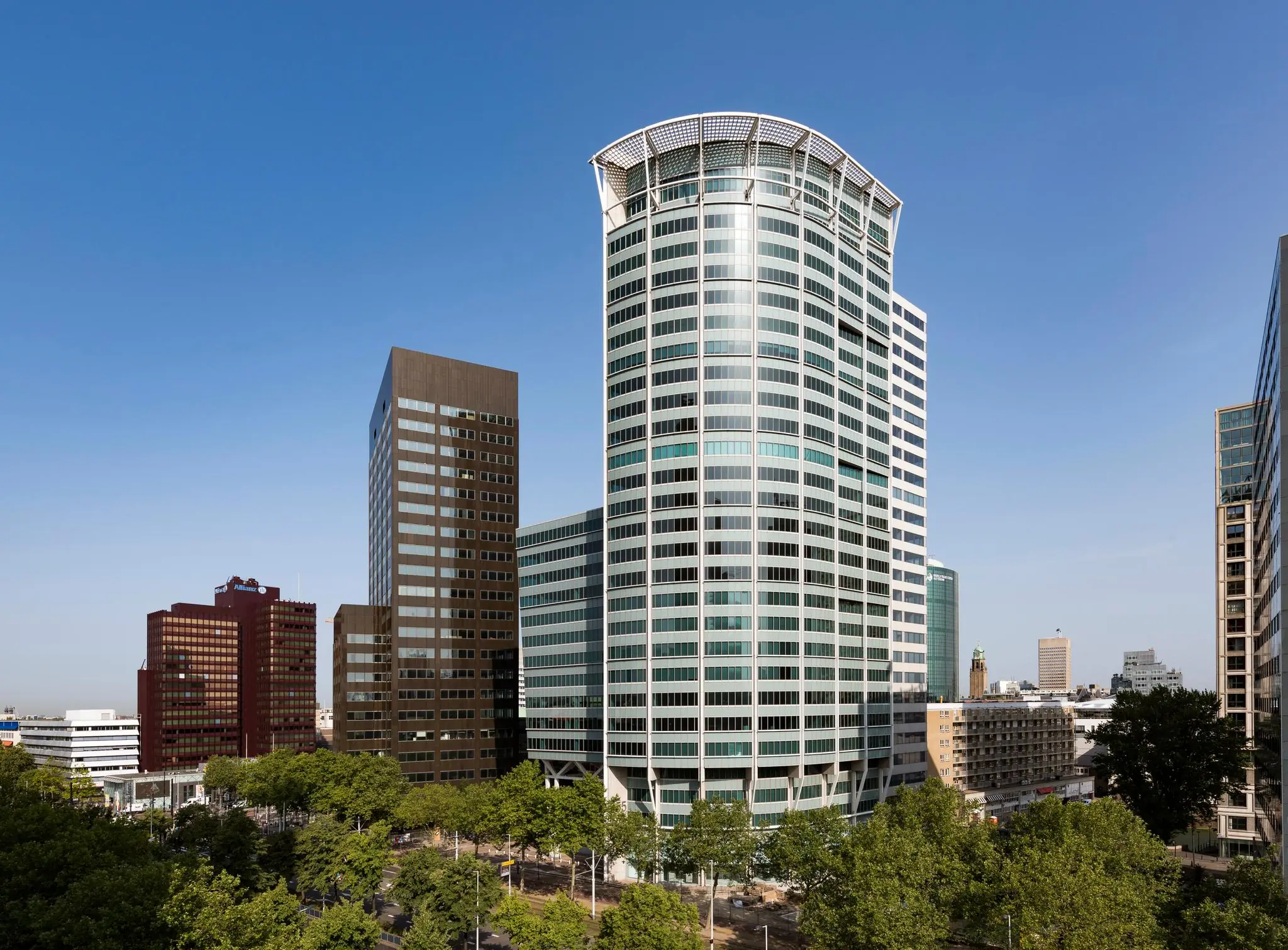 Hoog modern kantoorgebouw Blaak 555 in Rotterdam, omringd door andere hoogbouw en groene bomen.