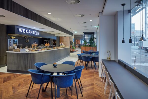 Moderne bedrijfskantine in Blaak 555 met zitgelegenheid, houten vloer en het buffet van "We Canteen".