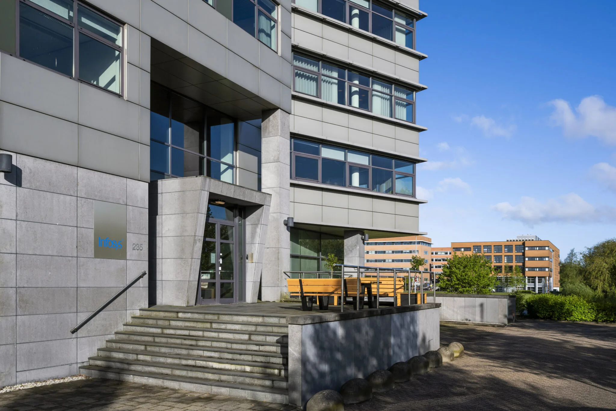 Voorgevel van het kantoorgebouw van Infosys aan de Boeing Avenue met een zitgedeelte en omliggende moderne bebouwing.