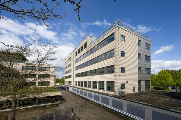 Modern kantoorgebouw aan de Boeingavenue met beige gevel en grote ramen, gefotografeerd op een zonnige dag.