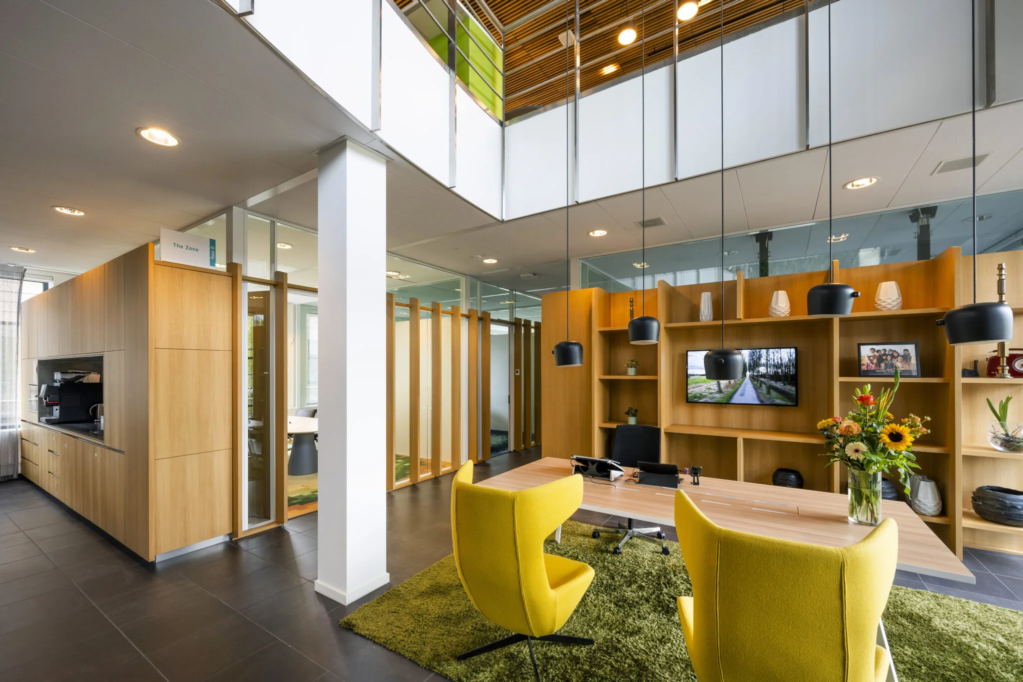 Modern kantoorinterieur aan de Boeing Avenue met een houten inrichting, gele stoelen, planten en hanglampen.