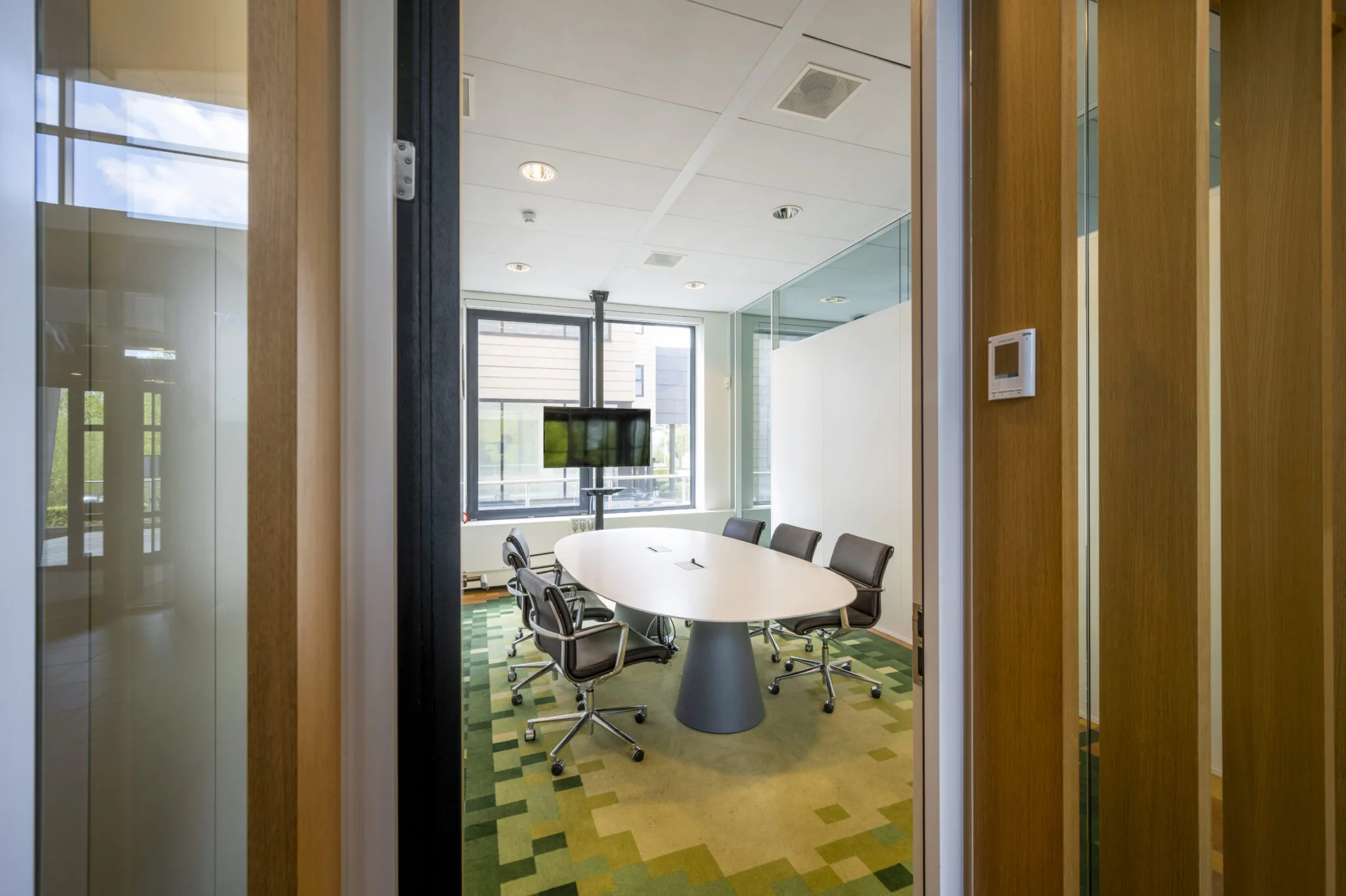 Vergaderruimte met ovale tafel, zes stoelen en een flatscreen in een modern kantoorpand aan de Boeing Avenue.