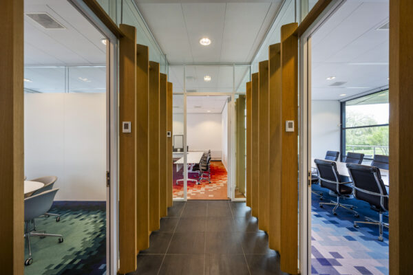Moderne kantoorruimte met houten wandpanelen en drie kleurrijke vergaderruimtes in Boeingavenue 043, ontworpen door Paul Starink.