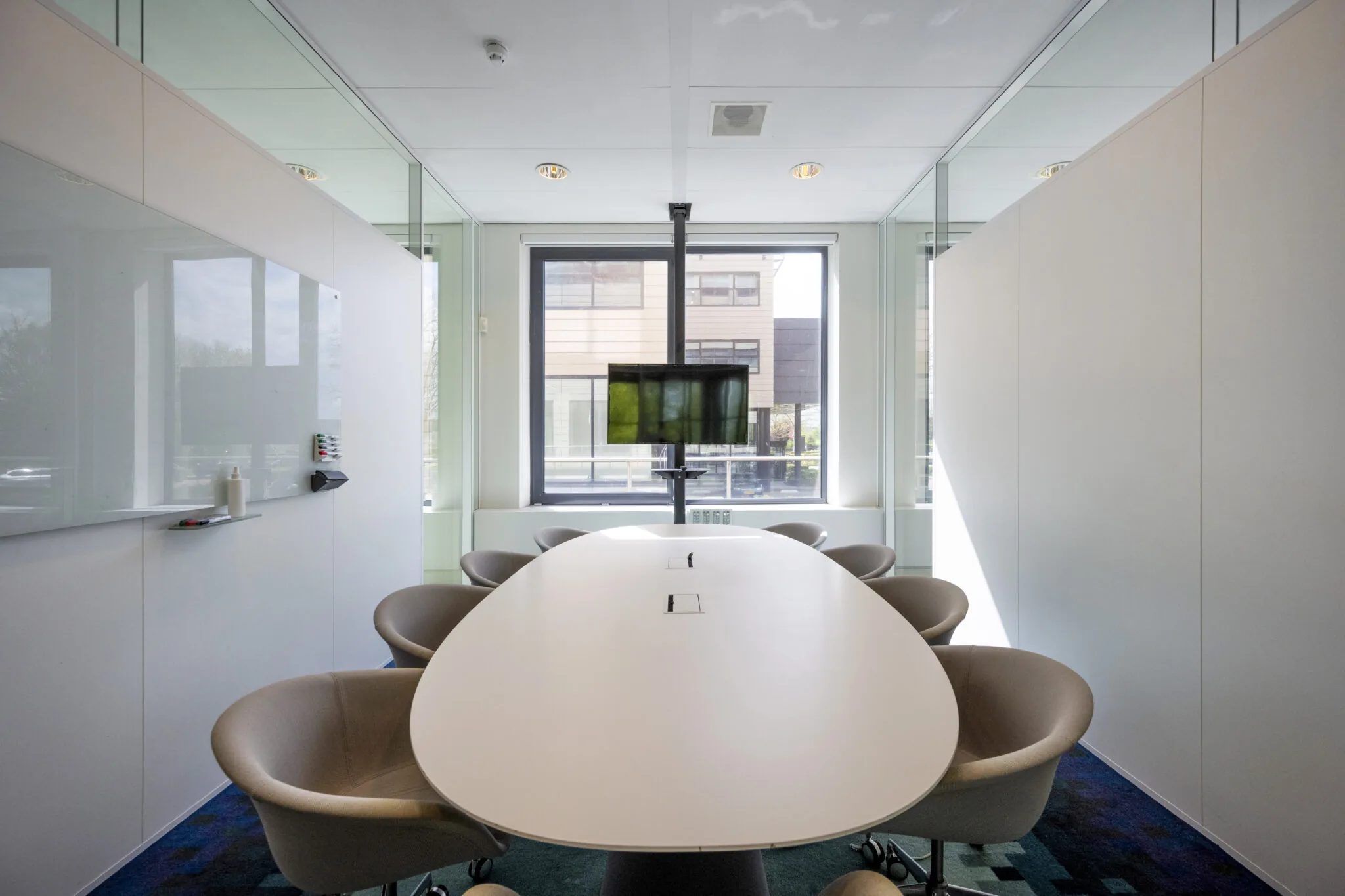 Vergaderruimte aan de Boeing Avenue met ovale tafel, moderne stoelen, tv-scherm en glazen wanden.