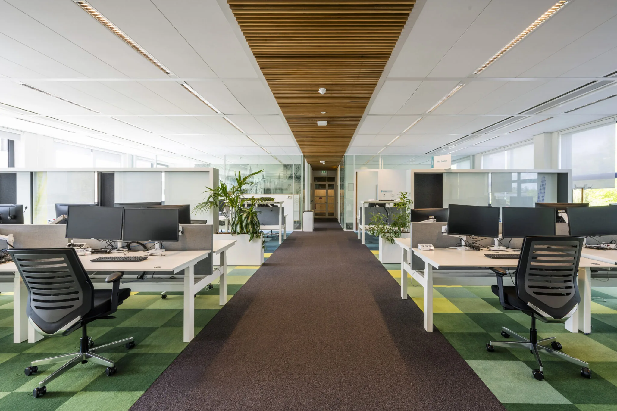 Modern open kantoorinterieur aan de Boeingavenue met ergonomische bureaustoelen, dubbele monitors en groene accenten.