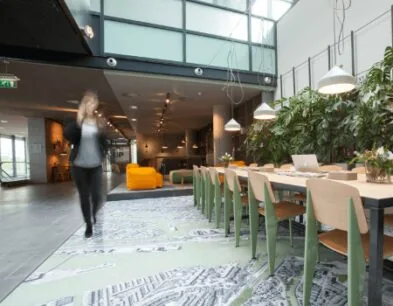 Moderne kantoorruimte met een lange vergadertafel, groene plantenwand en veel natuurlijk licht.