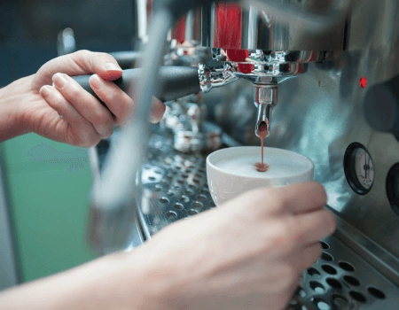 Barista maakt een kopje espresso met een professionele espressomachine.
