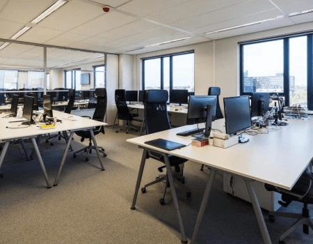 Moderne, open kantoorruimte met meerdere lege werkplekken en bureaustoelen.