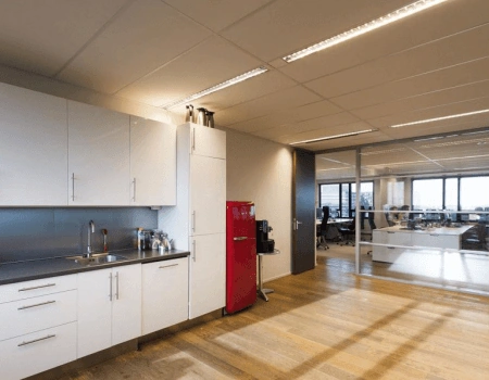 Moderne kantoorruimte met een open keuken en glazen wanden naar het werkgebied.