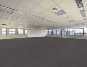 Lege, moderne kantoorruimte met systeemplafond, grote ramen en uitzicht op een stedelijk landschap.