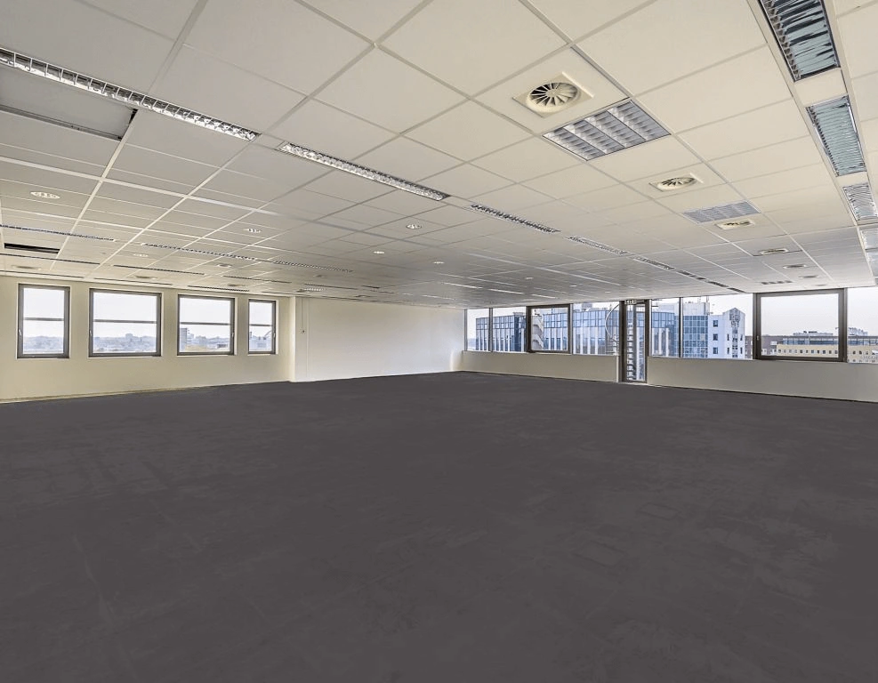 Lege, moderne kantoorruimte met systeemplafond, grote ramen en uitzicht op een stedelijk landschap.