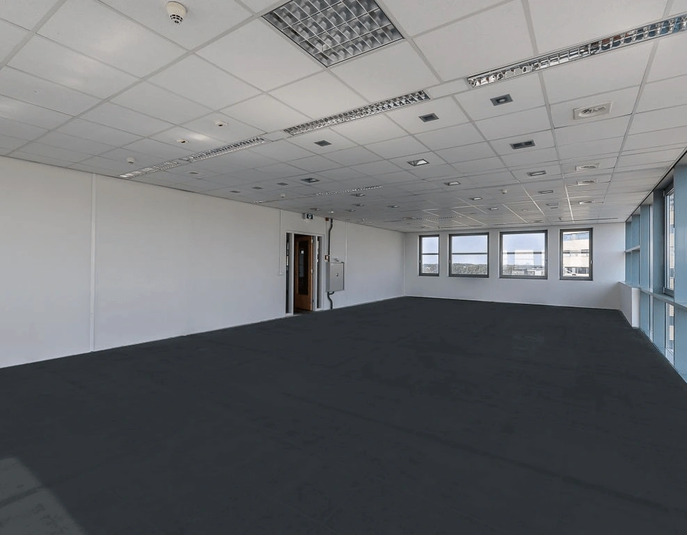 Lege, moderne kantoorruimte met systeemplafond, ramen en een geopende deur.