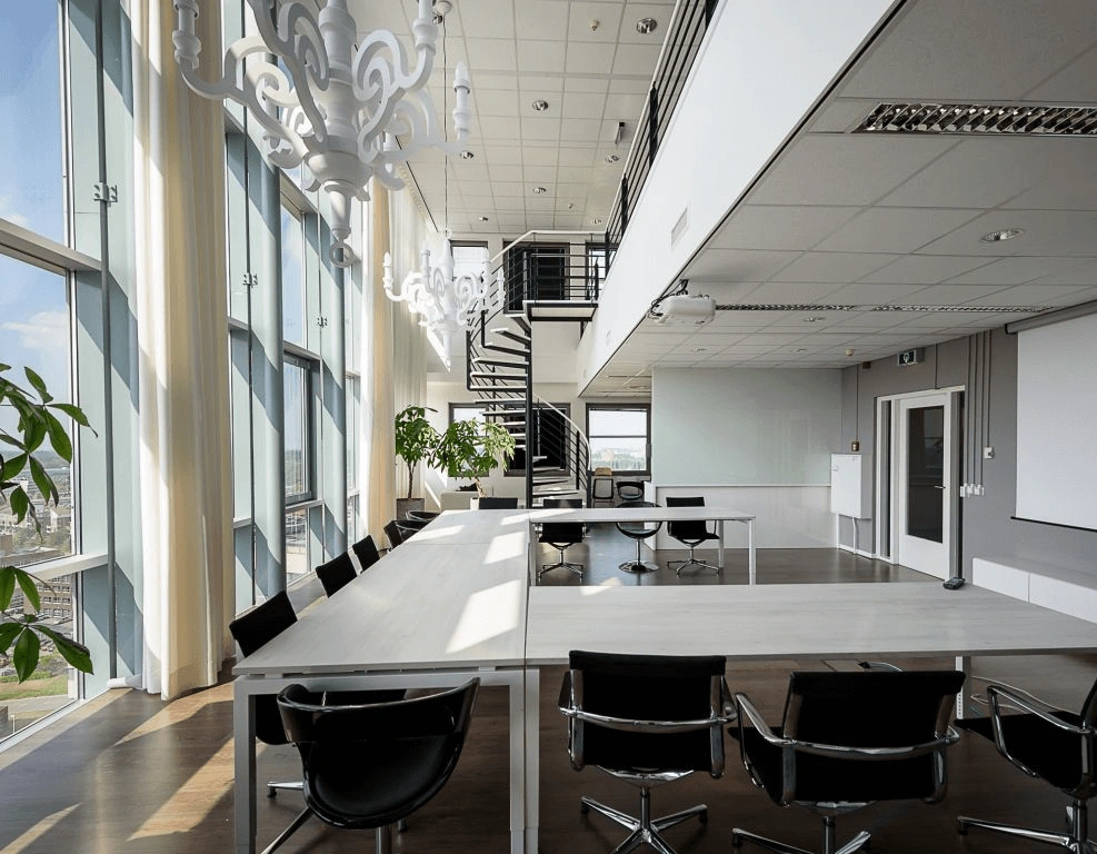 Moderne vergaderruimte met grote ramen, designkroonluchters en een open trap naar een bovenverdieping.