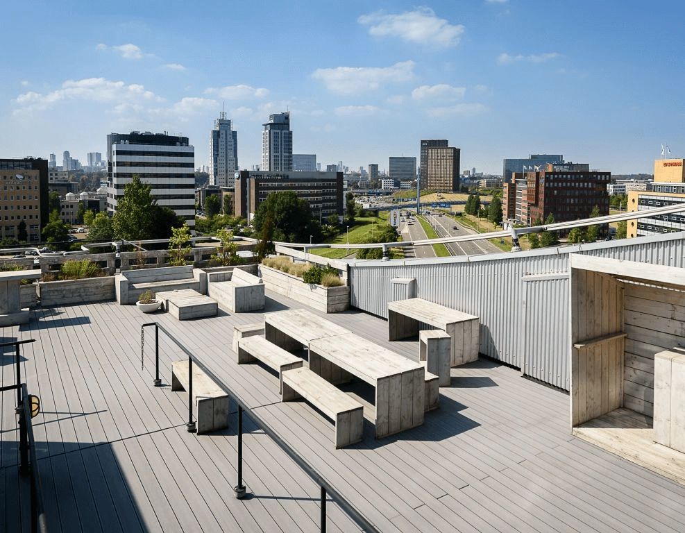 Dakterras met houten zitbanken en uitzicht op moderne kantoorgebouwen en een snelweg in een stedelijke omgeving.
