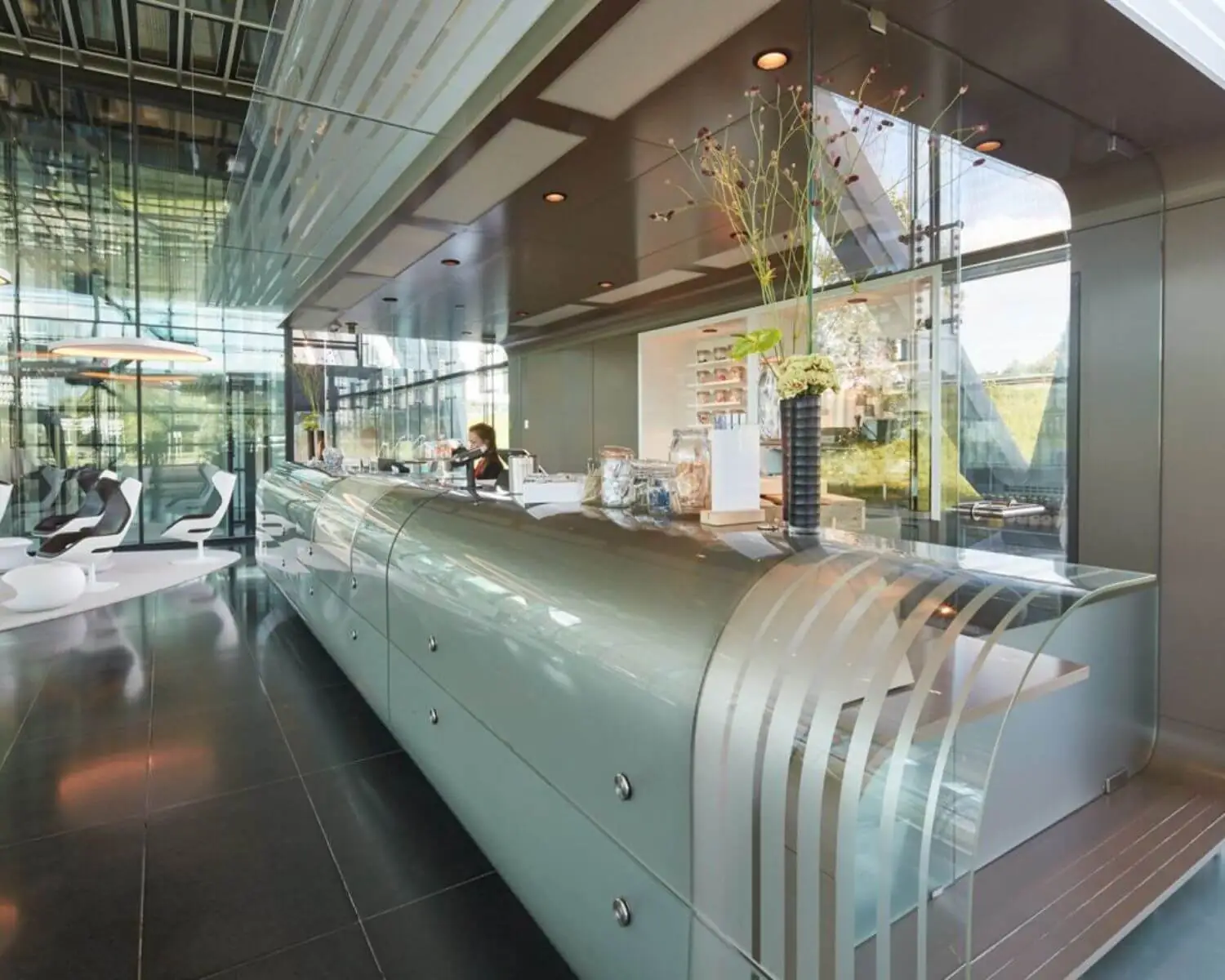 Moderne, glazen receptiebalie met een futuristisch design in een lichte en strakke kantoorlobby.