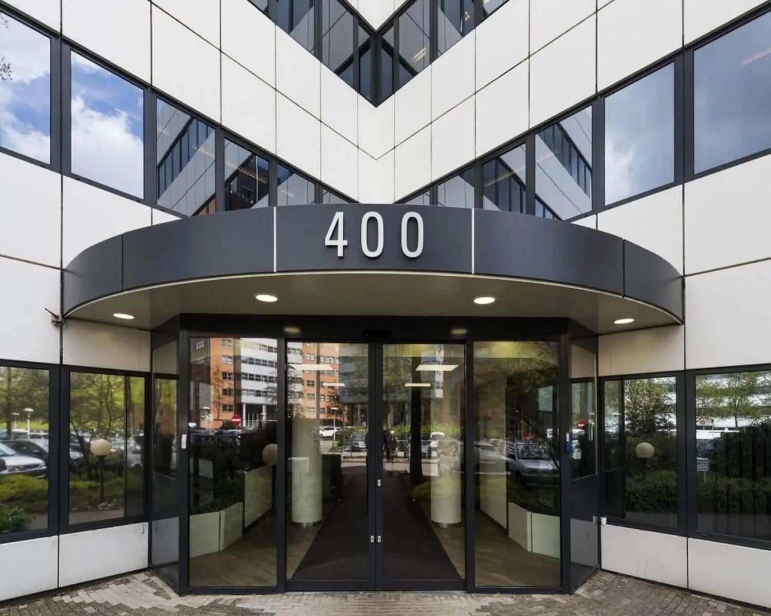 Ingang van een modern kantoorgebouw met het nummer 400 boven de deur.